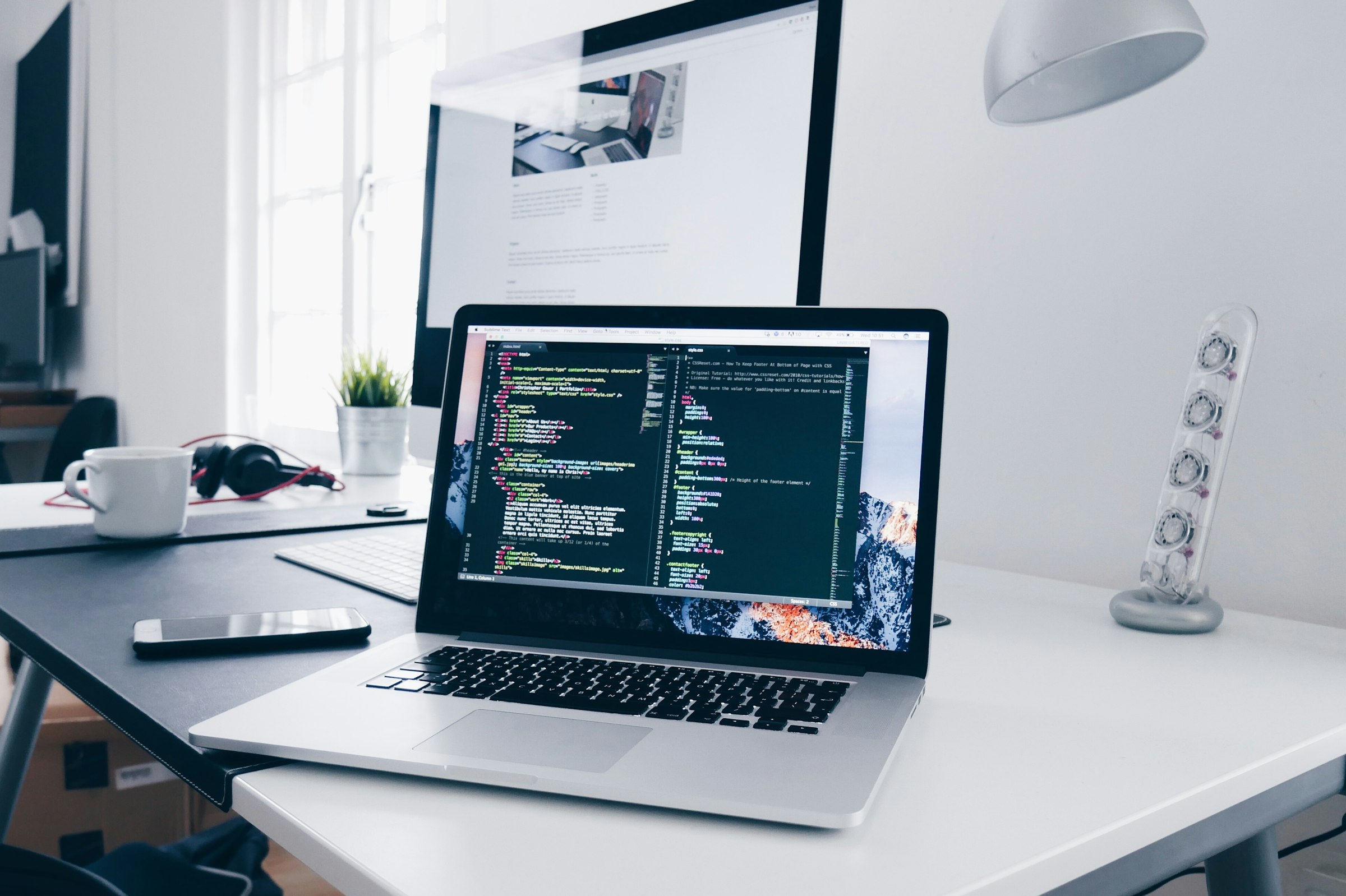 Laptop open on a desk with active web development code on screen